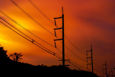 Low angle view of silhouette electricity pylon against romantic sky