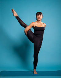 Full length of woman exercising against blue background