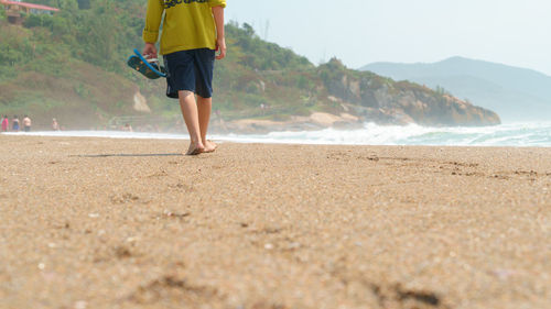 Low section of man on beach against sky