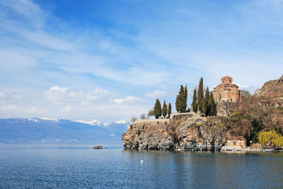 View of church at waterfront against cloudy sky