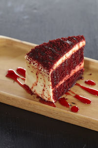 High angle view of red velvet cheesecake slice in wooden plate on table