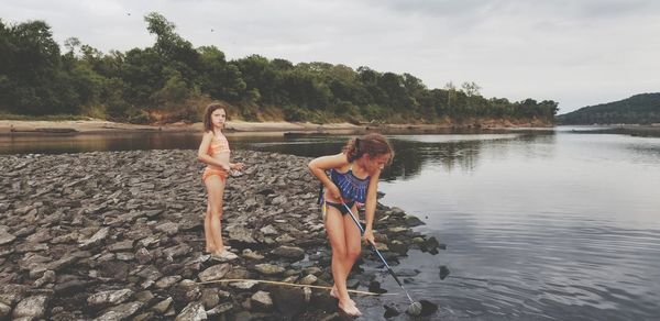 Girl standing with sister at lakeshore