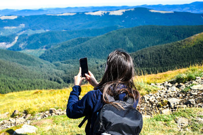Faceless girl taking photos in mountains. back view of woman blogger in mountain hiking. tourist 