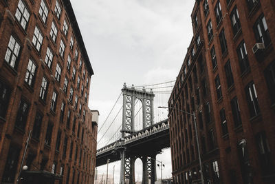 Low angle view of bridge and buildings against sky