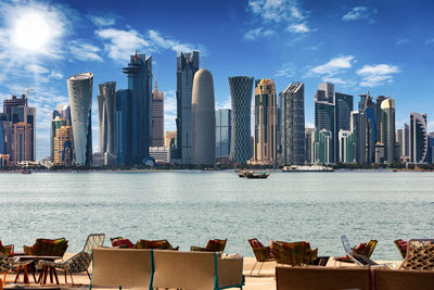 Outdoor cafe by river against skyline in city