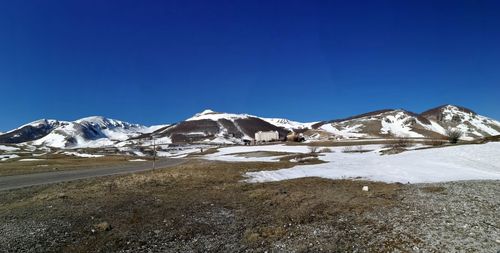 Scenic view of snowcapped mountains against clear blue sky