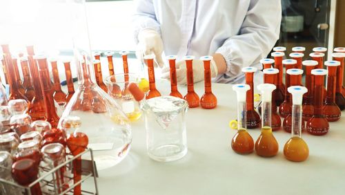 Midsection of man in glass bottles on table