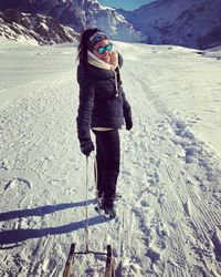 Full length portrait of young woman standing in snow