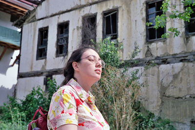 Young woman wearing eyeglasses standing against building