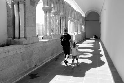 Rear view full length of mother walking with daughter in building passage