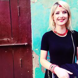 Portrait of smiling young woman standing against wall