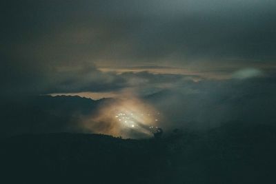 Silhouette mountains against cloudy sky at night