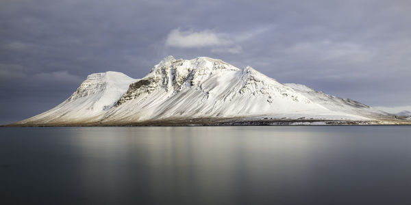 Scenic view of lake by snowcapped mountain against sky