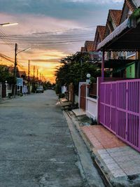 Street amidst buildings against sky during sunset