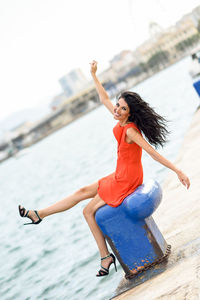 Portrait of cheerful woman sitting at harbor in city