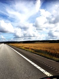 Surface level of empty road against cloudy sky