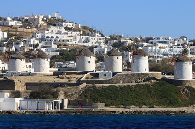Houses by sea against clear blue sky