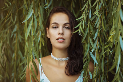 Portrait of beautiful young woman against plants