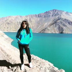 Full length portrait of young woman standing on mountain