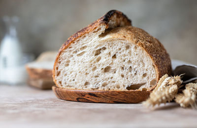 Loaf of fresh homemade sourdough bread on wooden plate with wheat ears