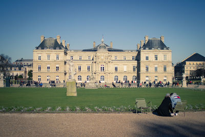 People in front of historical building against clear sky