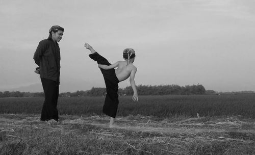 Man looking at son practicing martial arts on field