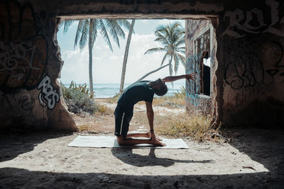 Full length of yoga man in park against wall