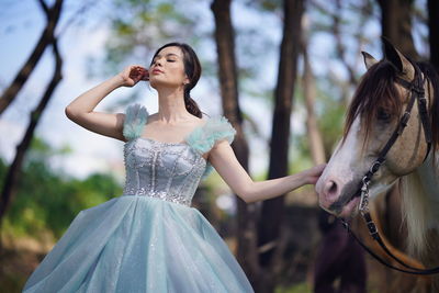 Portrait of a beautiful woman with a horse in the forest background.