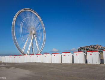 Low angle view of ferris wheel against clear blue sky