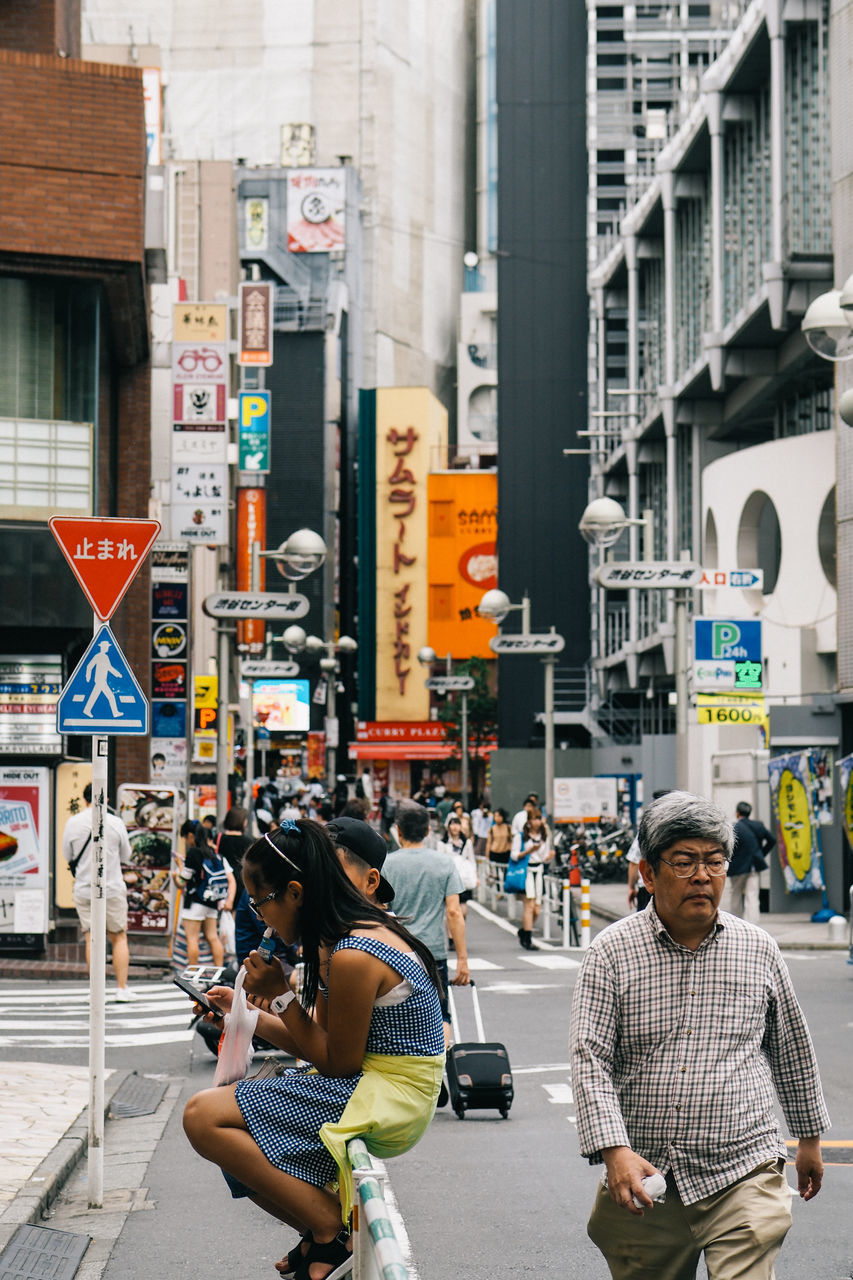 communication, real people, wireless technology, city, technology, transportation, lifestyles, men, walking, architecture, sitting, public transportation, outdoors, women, building exterior, day, road, people