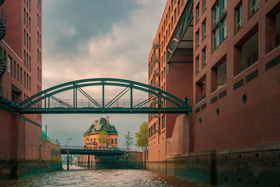 Low angle view of buildings by canal against sky in the city of hamburg, germany