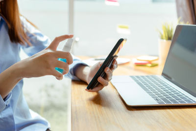 Midsection of woman using smart phone on table