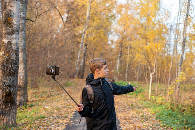 Teenage boy vlogging in autumn forest