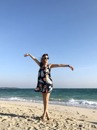 Full length of woman standing on beach against clear sky