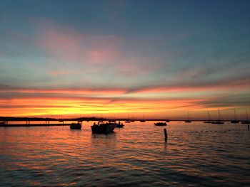 Silhouette boats in calm lake at sunset