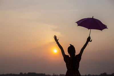 Silhouette woman standing by tree against sky during sunset