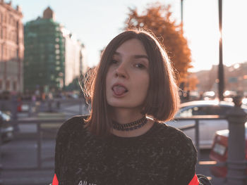 Portrait of woman sticking out tongue in city 