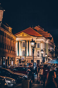 People in illuminated city against sky at night