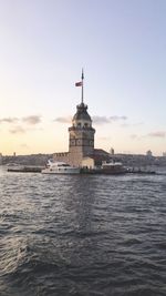 Lighthouse by sea against sky during sunset