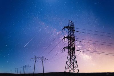 Low angle view of electricity pylon against sky at night