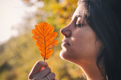 Close-up portrait of woman holding autumn leaves