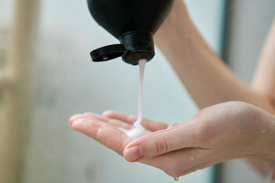 Woman pouring shampoo on hand in bathroom