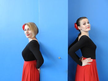 Young woman standing against blue wall