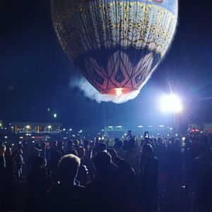 Group of people at music concert against sky at night