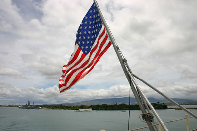 Flag flying over water against sky