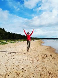 Full length of man jumping on beach against sky