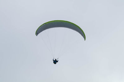 Low angle view of person paragliding against sky