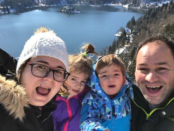 Portrait of happy family against lake during winter