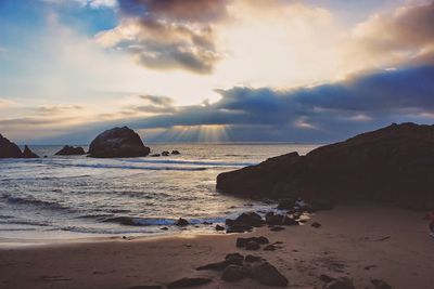 Rocks at beach against sky at morning