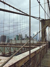 Bridge over railroad tracks in city against sky